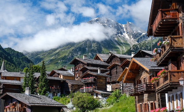 Traditional Swiss chalet with wooden architecture nestled among green Alpine mountains